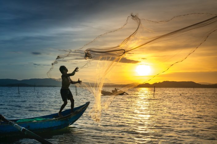 Person Throwing Fish Net While Standing On Boat 2131967